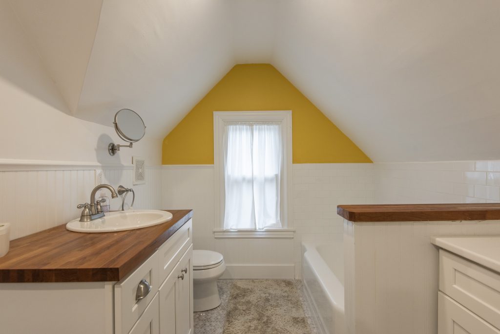 White attic bathroom with a yellow corner