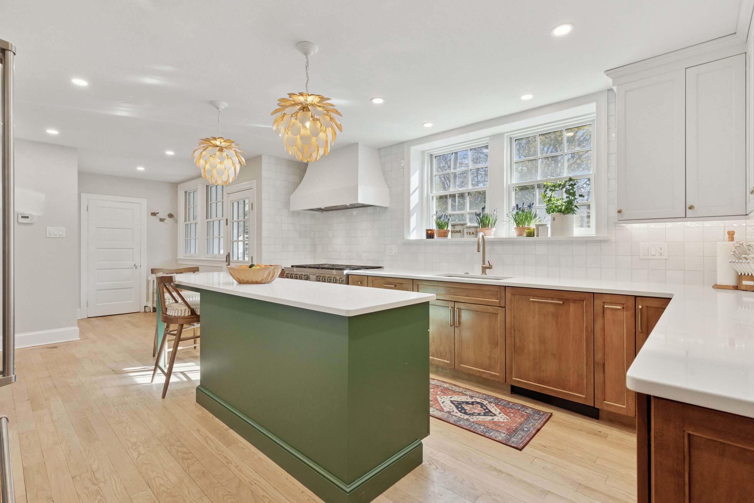 Modern kitchen with green island and artichoke pendant lights.